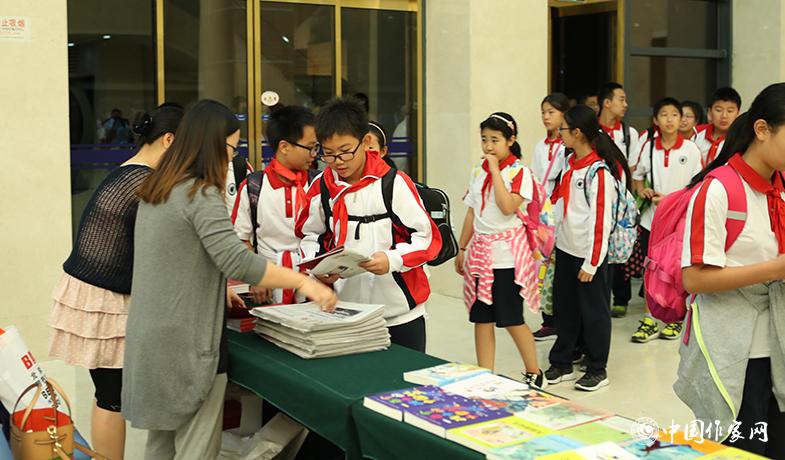 參加頒獎典禮的學生排隊入場，工作人員為他們分發當天的《文藝報》兒獎特刊